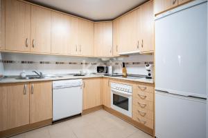 a kitchen with white appliances and wooden cabinets at Terraza y Parking - Ático Capitán - Koti Rentals in Fuengirola