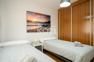 a bedroom with two beds and a painting on the wall at Terraza y Parking - Ático Capitán - Koti Rentals in Fuengirola