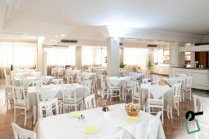 a dining room with white tables and white chairs at Hotiday Porto Cesareo in Porto Cesareo