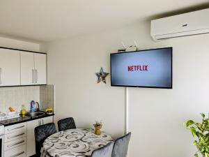 a kitchen with a table and a tv on the wall at Venus Apartman in Brčko