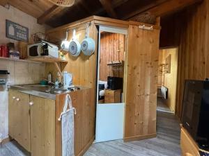 a kitchen in a wooden cabin with a sink and a refrigerator at Cabane du Bertic in Lège-Cap-Ferret +1 photo