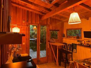 a kitchen with wooden walls and a dining room with a table at Cabane du Bertic in Lège-Cap-Ferret