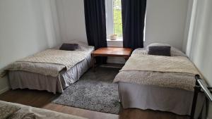 two beds in a room with a table and a window at Maria Isabelles boende nr 3 in Fjugesta