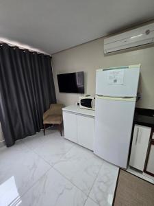 a kitchen with a white refrigerator and a microwave at Apartamento Central in Cascavel