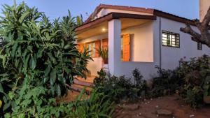a small white house with orange doors and trees at Tsanta lodge in Talata-maty