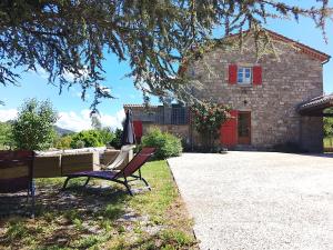 a bench in front of a house with a red shutter at La Maison du Bonheur in Jaujac
