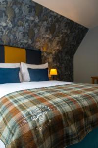 a bedroom with a bed with a plaid blanket at Kylesku Hotel & Kylesku House, by Highland Coast Hotels in Kylestrome