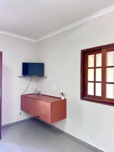 a living room with a tv on a white wall at quarto suíte privativo em campinas para até 4 pessoas in Campinas