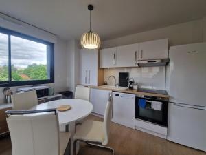 a kitchen with a table and a white refrigerator at Le Savannah #Parking#Terrasse in Clermont-Ferrand +2 photos
