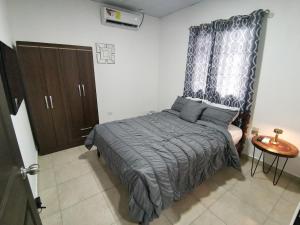 a bedroom with a bed with a blue blanket and a window at Casita del Valle in San Cristóbal