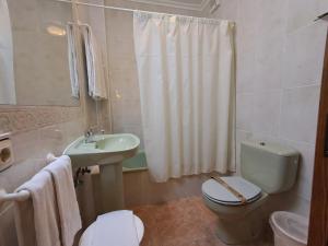 a bathroom with a toilet and a sink and a shower at Hostería La Casona in Noja