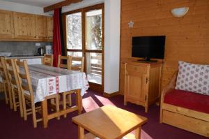 a kitchen and dining room with a table and a television at A27 Chalet du Galibier in Valloire