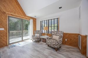 a living room with two chairs and a table and windows at 2507 - Salty Sandpiper in Duck