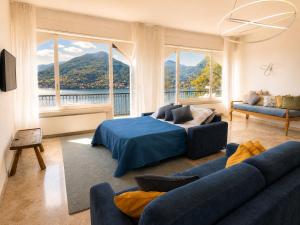 a bedroom with a bed and a couch and windows at Botanic Garden Lake Como in Blevio