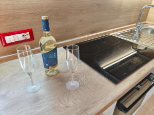a bottle of wine and two wine glasses on a counter at Monolocale moderno in centro storico in Scano Montiferro