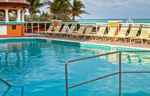 a swimming pool with chairs and the ocean in the background at Hollywood Beach Tower - Hotel Room in Hollywood