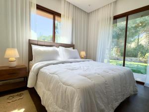a bedroom with a white bed with a large window at Le Forestier in Dar el Hajri