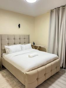 a bedroom with a large white bed with a large headboard at Victor Airport suites in Nairobi +15 photos