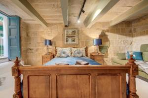 a bedroom with a wooden bed in a room with stone walls at Valletta Boutique Residence in Valletta