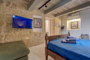 a bedroom with a bed and a tv on a stone wall at Valletta Boutique Residence in Valletta +25 photos