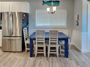 a kitchen with a blue table and a refrigerator at Port As Flip Flops & Pop Tops in Port Aransas +24 photos