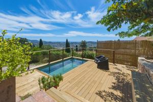 a wooden deck with a swimming pool in a backyard at Villa vue mer panoramique & piscine chauffée in Toulon