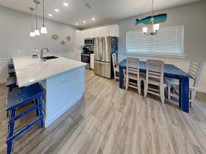 a kitchen with a blue island and a table with chairs at Port As Flip Flops & Pop Tops in Port Aransas