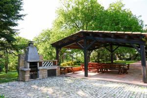 a pavilion with a grill and picnic tables in a park at Mas Joanmiquel - Masía histórica exclusiva in Les Olives
