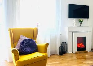 a yellow chair with a purple pillow in a living room with a fireplace at APSTAY City Residence Apartments ǀ Parking option & Self Check-in in Graz +29 photos