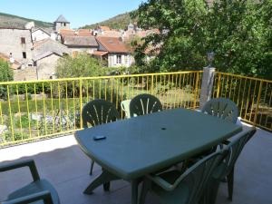 a green table and chairs on a balcony at Oustalou in Saint-Rome-de-Tarn