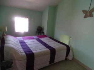 a bedroom with a bed with a purple and white blanket at Oustalou in Saint-Rome-de-Tarn