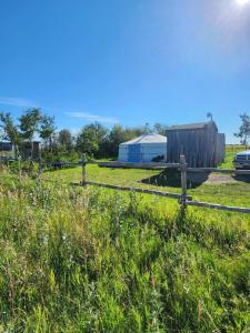 a fence in a field with a barn and a dog at COTC - The Coulee Yurt - Suite in Castor