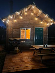 a wooden deck with a picnic table and lights at COTC - The Grouse House - Suite in Castor