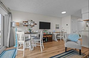 a living room with a table and chairs and a tv at Mystic Sands in Emerald Isle