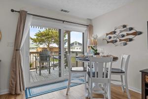 a dining room with a table and chairs and a balcony at Mystic Sands in Emerald Isle