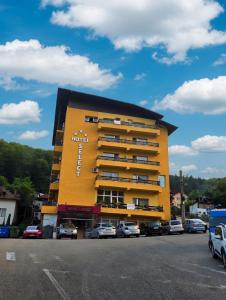 a yellow building with cars parked in a parking lot at Hotel Select in Băile Olăneşti
