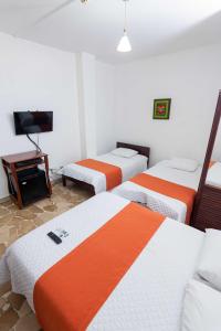 a hotel room with three beds and a television at Hotel de Alborada - Cerca Del Aeropuerto in Guayaquil