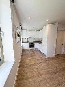 an empty kitchen with white cabinets and wood floors at Blanco Brillo in Colchester