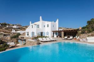 a villa with a swimming pool in front of a house at Cozy Villa in Mykonos