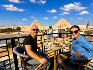 two people sitting at a table in front of the pyramids at Dima Plaza Pyramids View in Cairo