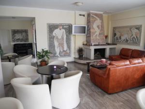 uma sala de estar com um sofá de couro e cadeiras brancas em Hotel Apollon em Rio