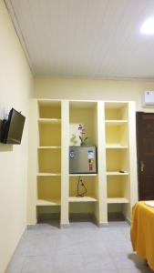 a room with yellow shelves and a tv on a wall at POUSADA CANEDO in Guaibim