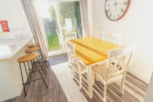 a dining room with a table and chairs and a clock at Glenroy House Swansea in Swansea