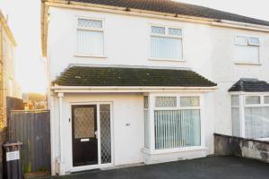 a white house with a black door and windows at Glenroy House Swansea in Swansea
