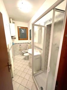a bathroom with a toilet and a glass shower door at Casa Ariel in Lido Adriano +12 photos
