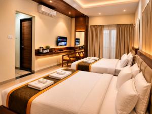 a hotel room with two beds and a desk at Hotel Unnati Stay Inn Vijayapura By HRG in Bijāpur