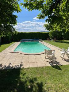 a swimming pool with two chairs in a yard at Appartement 2 in Sauzet