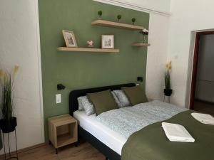 a bedroom with a bed with a green wall at Balaton Bloom 24 in Siófok