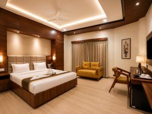 a hotel room with a bed and a chair at Hotel Unnati Stay Inn Vijayapura By HRG in Bijāpur