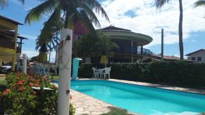 a swimming pool in front of a house with a palm tree at POUSADA CANEDO in Guaibim